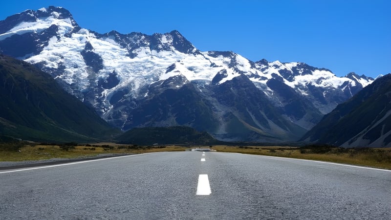 Eine verschlungene Straße führt durch ein weites, schneebedecktes Gebirge unter klarem Himmel mit Bezug zur Westlake Boys High School.