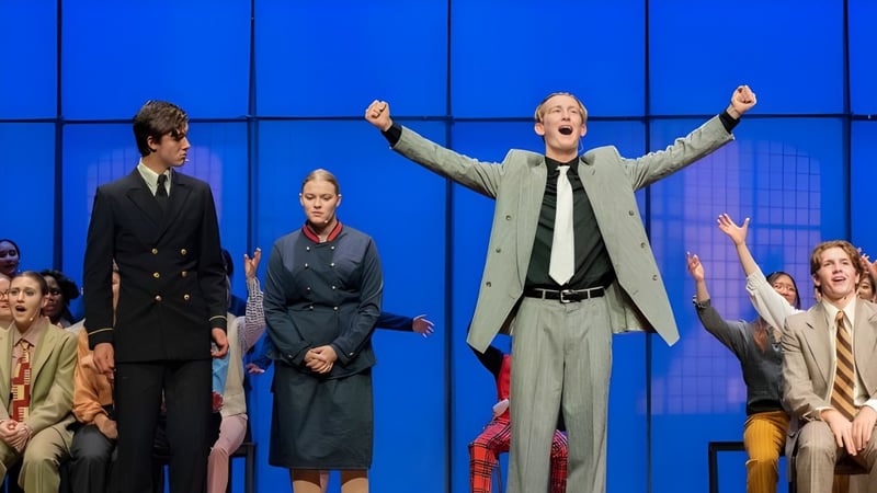 Schüler der Westminster School führen eine Theateraufführung auf einer Bühne vor einem blauen Hintergrund auf.