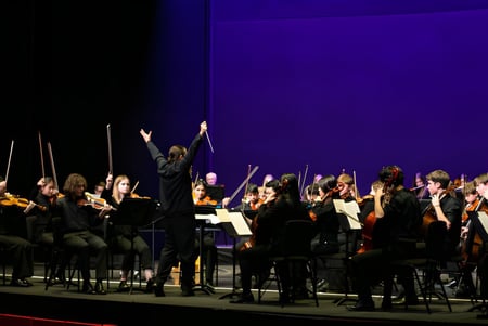 Das Orchester der Westonbirt School spielt auf der Bühne unter der Leitung eines Dirigenten.