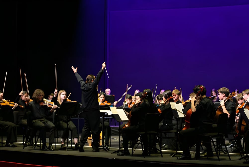 Das Orchester der Westonbirt School führt auf der Bühne ein Konzert unter Leitung des Dirigenten auf.