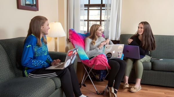 Drei Schülerinnen der Westover School sitzen auf einer Couch und arbeiten mit ihren Laptops im Gemeinschaftsraum.
