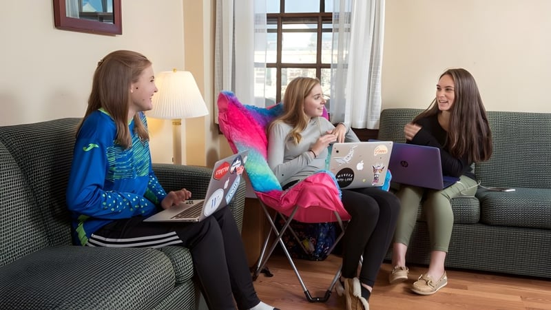 Drei Schülerinnen der Westover School sitzen auf einer Couch und arbeiten gemeinsam an Laptops.