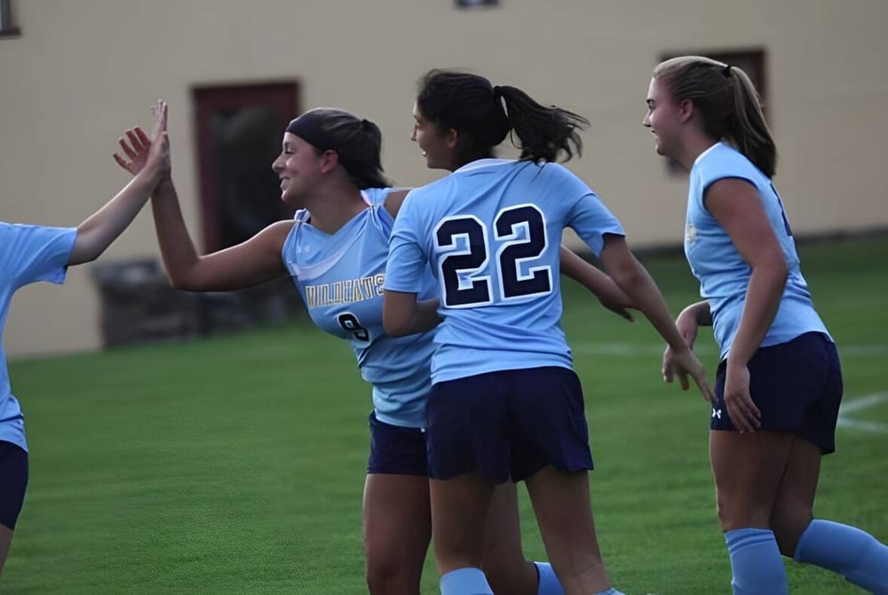 Eine Gruppe junger Sportlerinnen steht auf einem Rasenfeld auf dem Campus der Westover School.