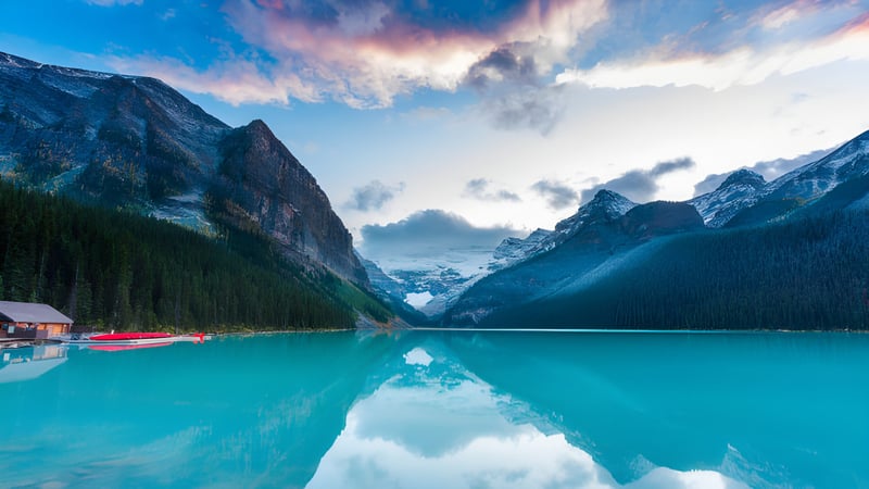 Ein ruhiger türkisfarbener See vor schneebedeckten Bergen auf dem Gelände der Westside Secondary School.