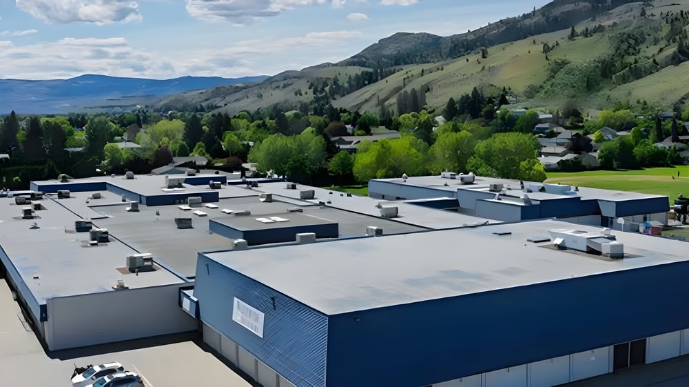 Eine Berglandschaft mit einer Stadt im Tal und modernen blauen Gebäuden vor der Westsyde Secondary School.