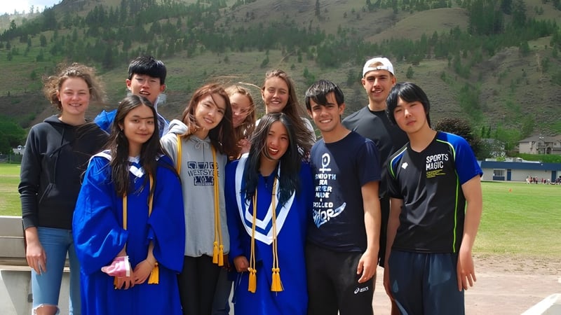 Eine Gruppe Schülerinnen und Schüler der Westsyde Secondary School posiert vor einem bewaldeten Bergpanorama.