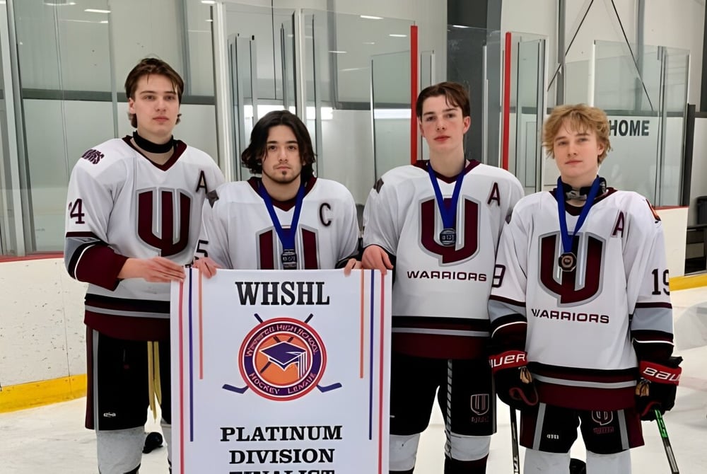 Eine Gruppe junger Hockeyspieler hält im Westwood Collegiate vor einer Eishalle ein Banner der WESHL Platinum Division.