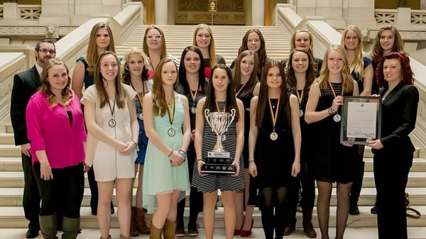 Eine Gruppe Schülerinnen der Westwood Collegiate steht gemeinsam mit einem Pokal vor einem prächtigen Gebäude.