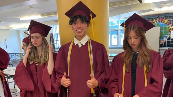 Eine Gruppe von Schülerinnen und Schülern der Westwood High School steht in Abschlussgewändern zusammen.