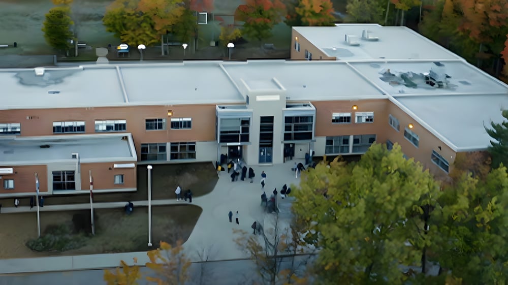 Das mehrstöckige Gebäude mit Glasfassade auf dem Campus der Westwood High School ist im herbstlichen Umfeld mit Bäumen und Menschen zu sehen.