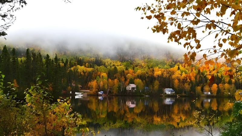 Ein ruhiger See umgeben von herbstlichem Laub vor bewaldeten Hügeln nahe der Westwood High School.
