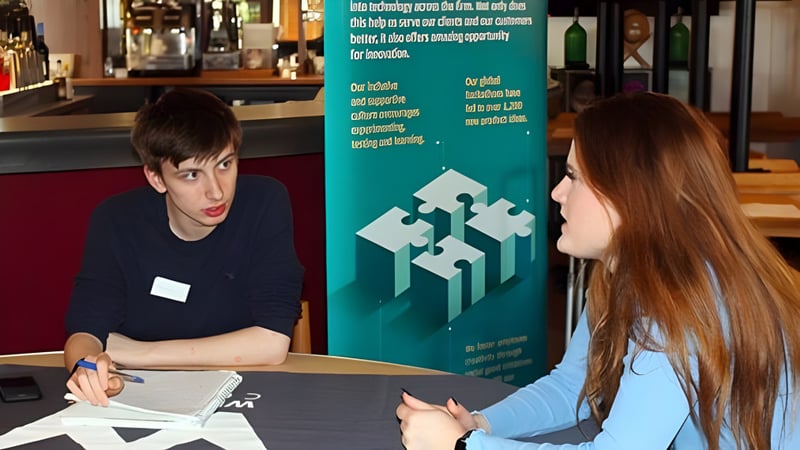 Zwei Personen führen ein Gespräch in einem Café auf dem Campus des Weymouth College.