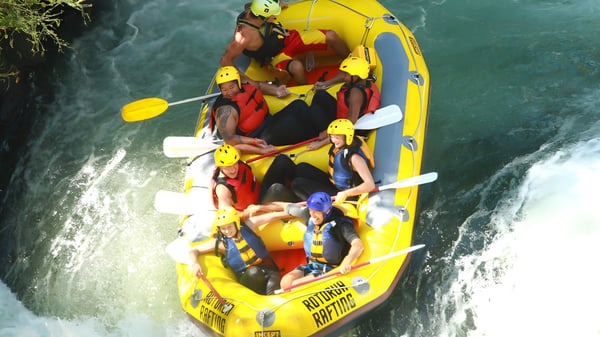 Schüler der Whakatane High School fahren mit einem gelben Schlauchboot den Fluss entlang.