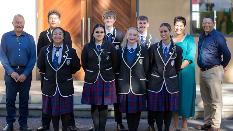 Eine Gruppe von Schülerinnen und Schülern steht vor einem bunten Hintergrund auf dem Campus des Whanganui City College.
