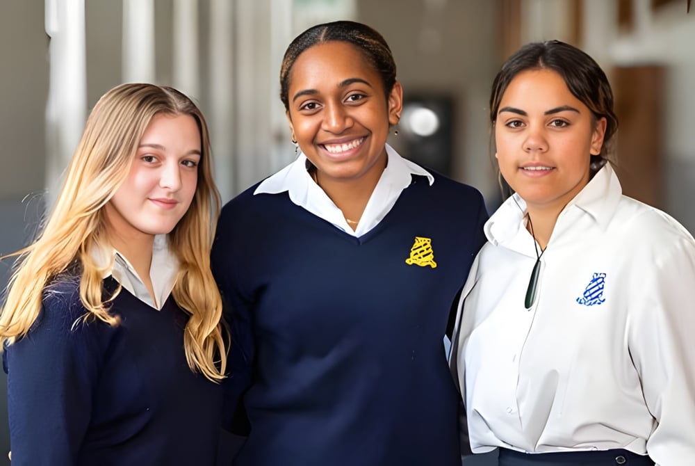 Drei Schülerinnen und Schüler stehen zusammen im Flur des Whanganui Girls’ College und tragen Schuluniformen.