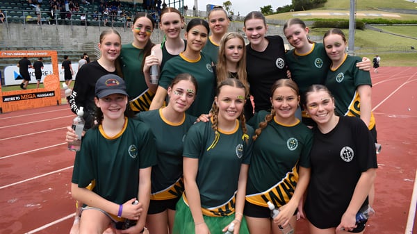 Eine Gruppe junger Athletinnen posiert in grünen und gelben Trikots auf dem Sportplatz des Whanganui Girls’ College.