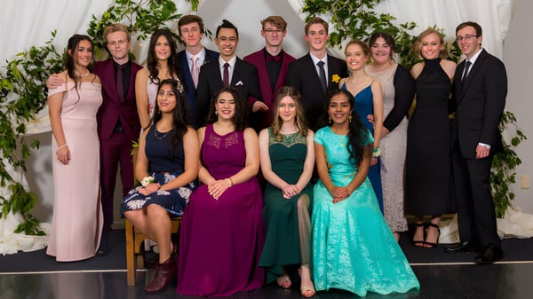 Eine Gruppe formell gekleideter Personen posiert vor einem Blumenhintergrund auf dem Gelände der Whanganui High School.