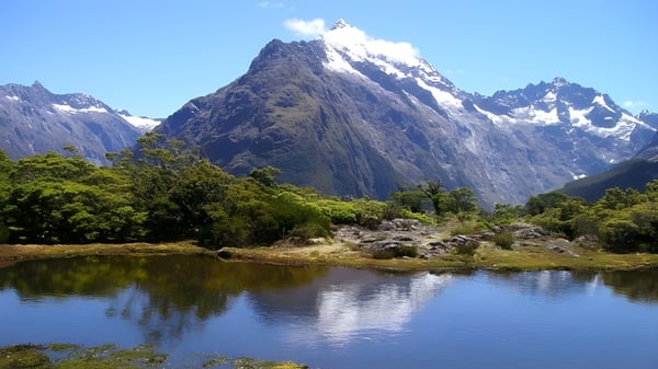 Ein See spiegelt schneebedeckte Berge wider, umgeben von grüner Vegetation, ohne direkte Verbindung zur Whanganui High School.
