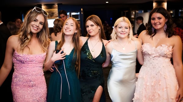 Fünf Schülerinnen des Whangaparāoa College posieren gemeinsam bei einer formellen Veranstaltung vor dunklem Hintergrund.