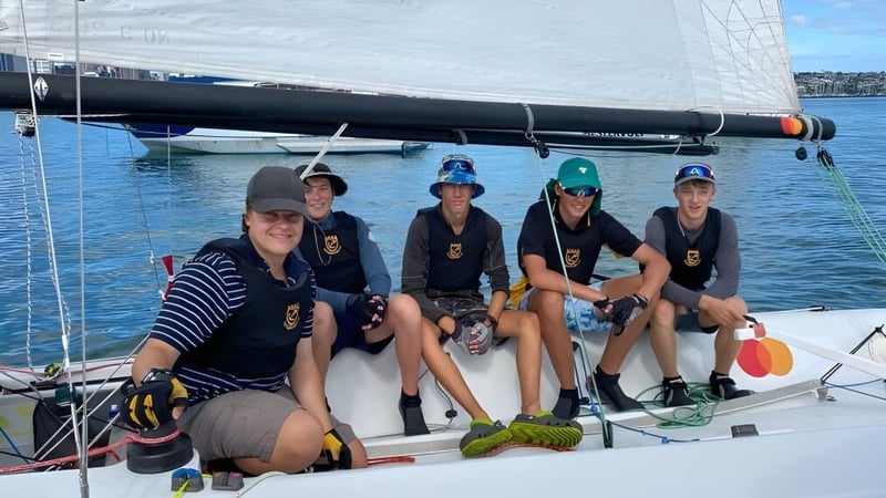 Schüler der Whangarei Boys’ High School sitzen im einheitlichen Dress auf einem Segelboot auf offenem Wasser.