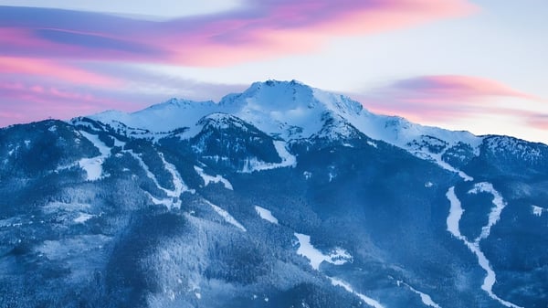 Eine beeindruckende Berglandschaft mit schneebedeckten Gipfeln vor farbigem Himmel in der Umgebung der Whistler Secondary School.
