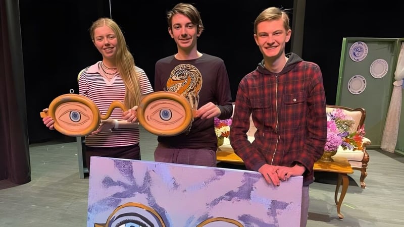 Drei Schülerinnen und Schüler der Whistler Secondary School halten bunte runde Objekte während einer Bühnenperformance.