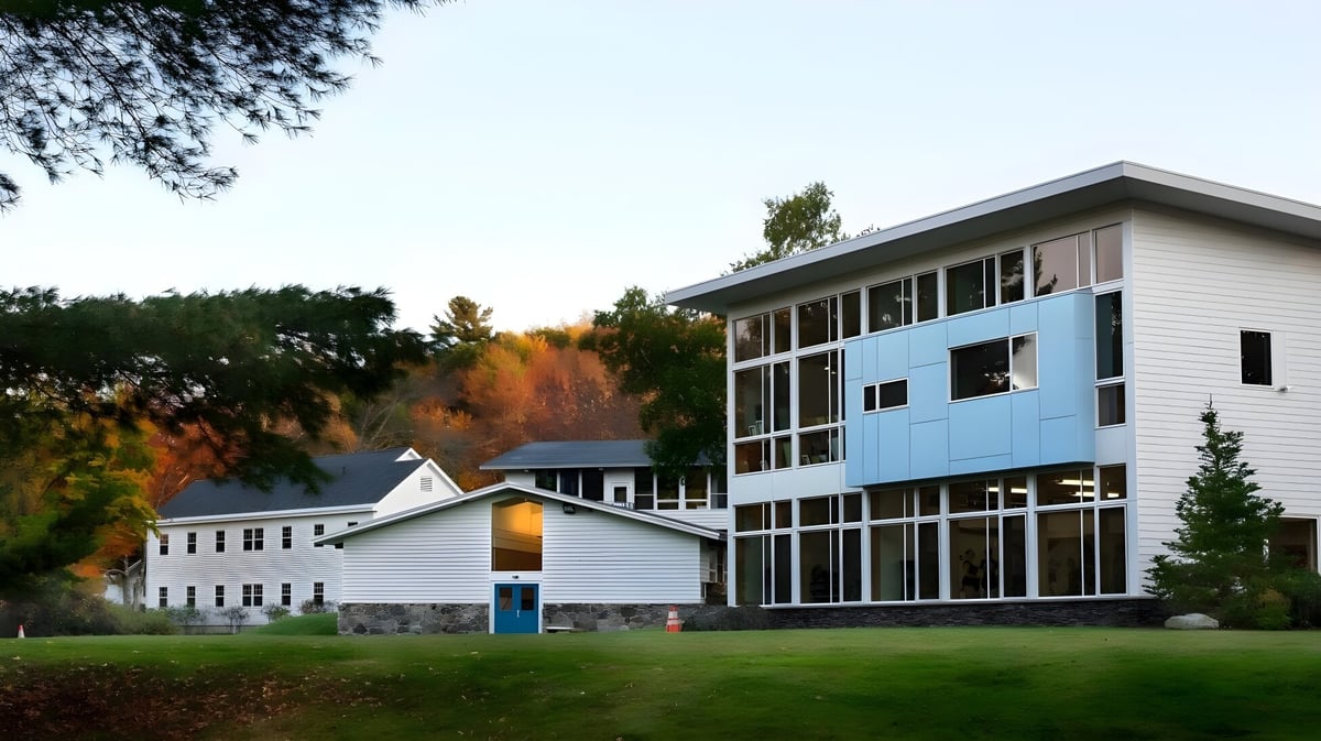 Das mehrstöckige Gebäude der White Mountain School ist von Bäumen mit Herbstlaub umgeben.