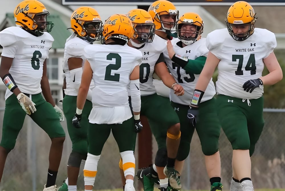 Eine Gruppe von Fußballspielern in grünen und weißen Trikots steht vor einem Gebäude auf dem Gelände der White Oaks Secondary School.