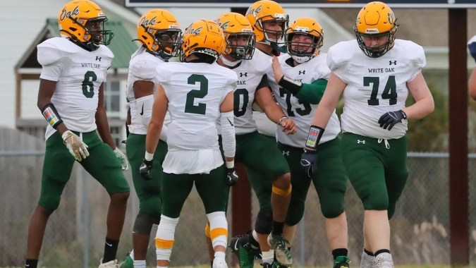 Eine Gruppe von Fußballspielern steht auf dem Spielfeld der White Oaks Secondary School vor einer Anzeigetafel.