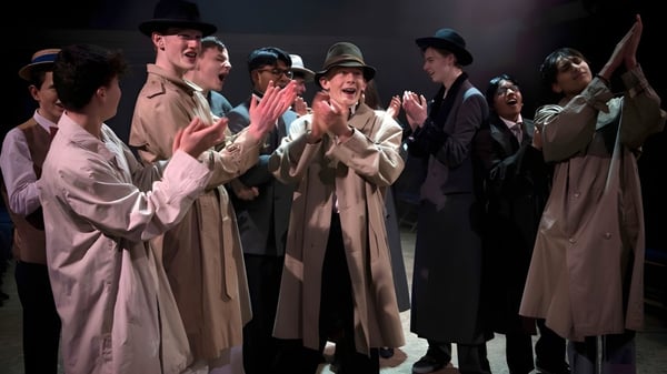 Eine Gruppe von Schülern der Whitgift School trägt lange Gewänder und Hüte bei einem Bühnenauftritt.