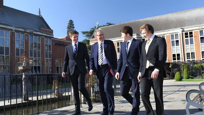 Vier Männer in formeller Kleidung stehen zusammen vor einem Gebäude auf dem Campus der Whitgift School.