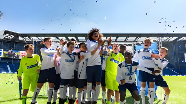 Schüler der Whitgift School feiern gemeinsam auf dem Fußballfeld mit Stadion im Hintergrund.