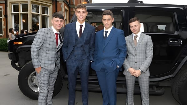 Eine Gruppe von Schülern der Whitgift School in Anzügen steht vor einem großen schwarzen Fahrzeug auf einer Straße in der Stadt.