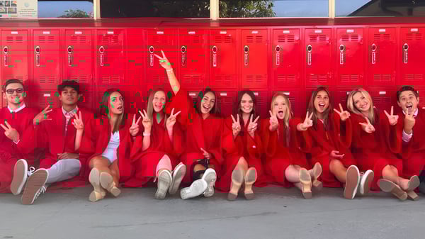 Schülerinnen der Whittier Christian High School sitzen in roten Uniformen vor einer Reihe roter Spinde.