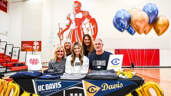 Schüler und Mitarbeiter der Whittier Christian High School stehen an einem Promotionstisch mit einem großen Wandbild im Hintergrund.