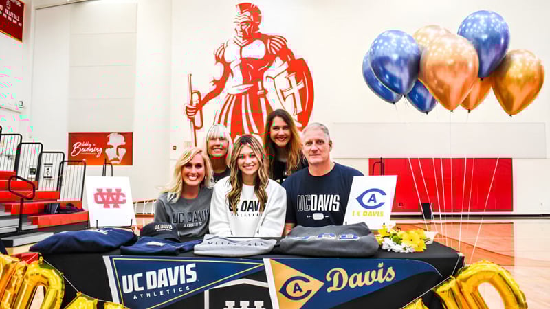 Schüler und Mitarbeiter der Whittier Christian High School stehen an einem Promotionstisch mit einem großen Wandbild im Hintergrund.