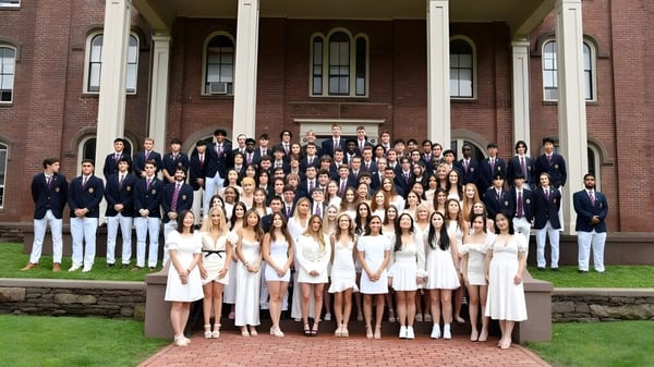 Eine Gruppe Schülerinnen und Schüler steht in formeller Kleidung vor dem historischen Gebäude der Wilbraham & Monson Academy.