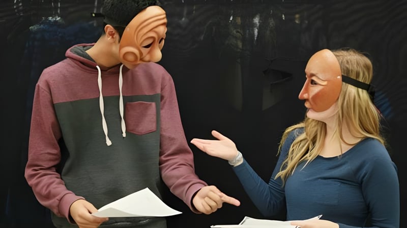 Zwei Schülerinnen der William Aberhart High School führen in einem dunklen Raum eine Interaktion durch.