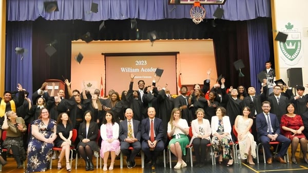 Eine Gruppe von Schülern und Erwachsenen auf der Bühne der William Academy bei einer Veranstaltung 2023.