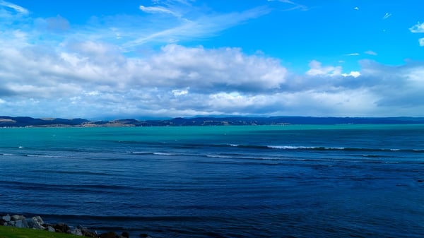 Blick auf den Ozean mit Bergen am Horizont vom Gelände des William Colenso College.