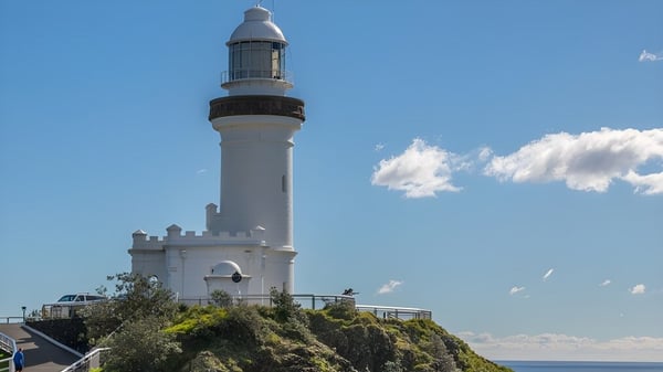 Ein hoher weißer Leuchtturm steht auf einem felsigen Vorsprung mit Blick auf den Himmel und das Meer bei der William Ross State High School.