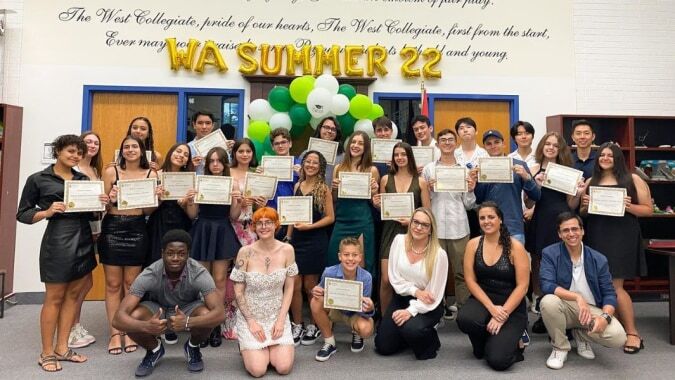 Schüler der William Academy posieren mit Zertifikaten für ein Gruppenfoto vor dem WA SUMMER '22 Schild.