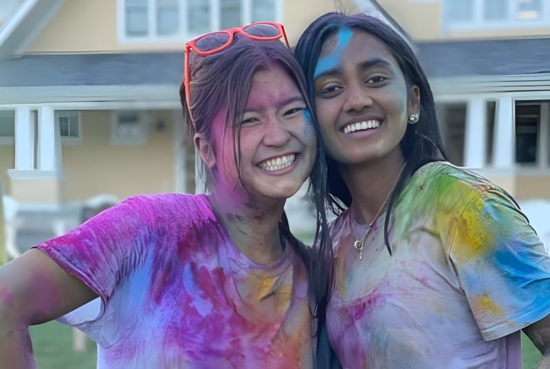 Zwei Schülerinnen der The Williston Northampton School stehen lachend vor einem Gebäude mit festlicher Atmosphäre.