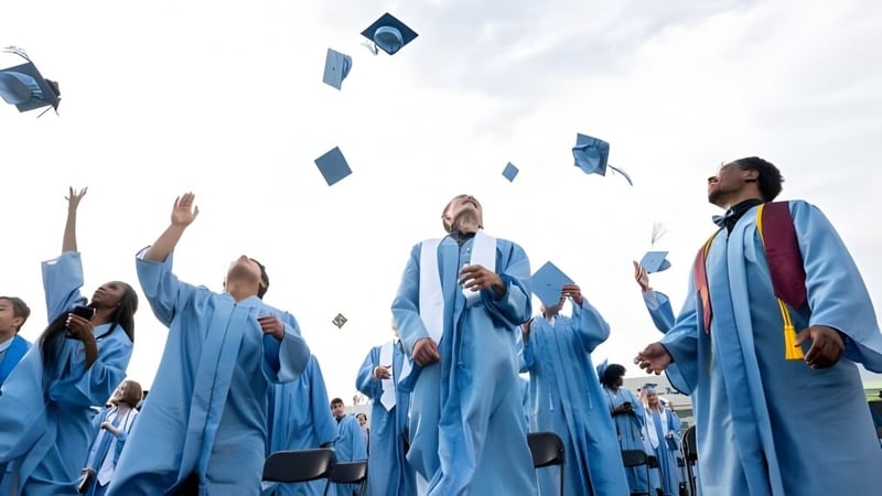 Eine Gruppe von Absolventinnen und Absolventen der Willow Creek Composite High School wirft ihre Abschlussmützen in den Himmel.