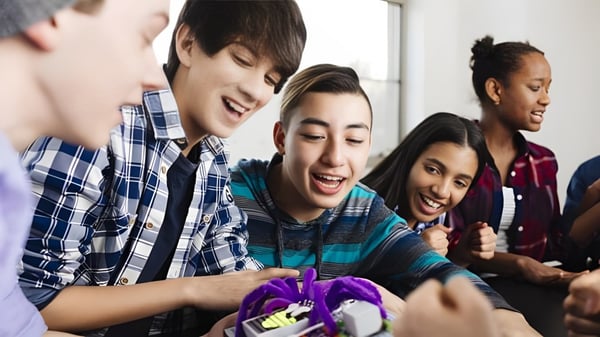 Eine Gruppe von Schülern der Willow Creek Composite High School führt eine spielerische Unterhaltung in einem Innenraum.