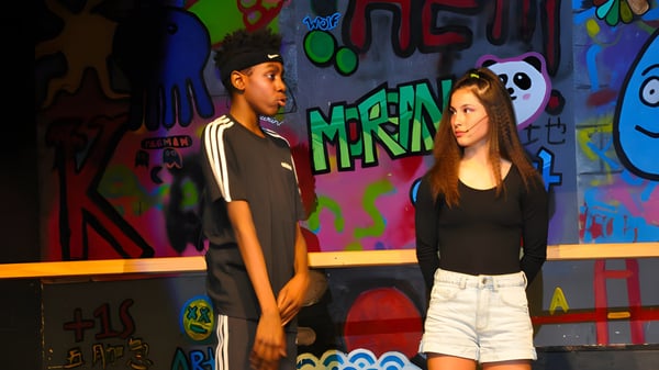 Zwei Schüler der WillowWood School stehen vor einer bunt besprühten Graffiti-Wand.