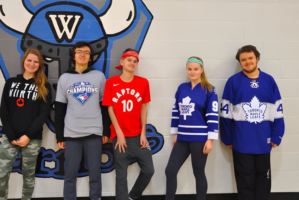 Eine Gruppe von Schülerinnen und Schülern der WillowWood School posiert vor einem großen Sport-Wandbild.