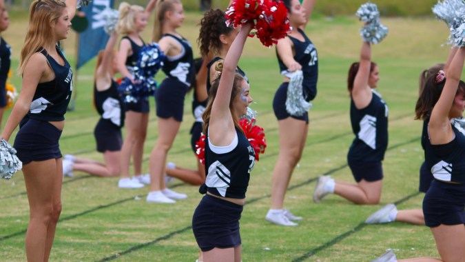 Eine Gruppe von Cheerleadern der Willunga High School führt auf einem Rasenfeld eine synchronisierte Routine aus.