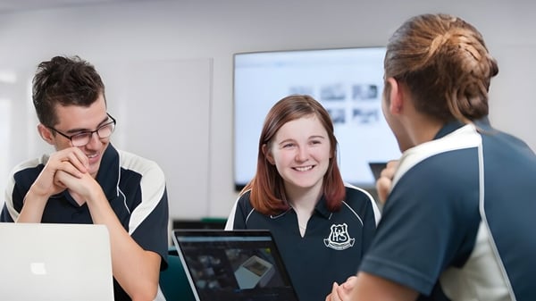 Drei Personen führen ein Gespräch in einem akademischen Umfeld auf dem Campus der Willunga High School.