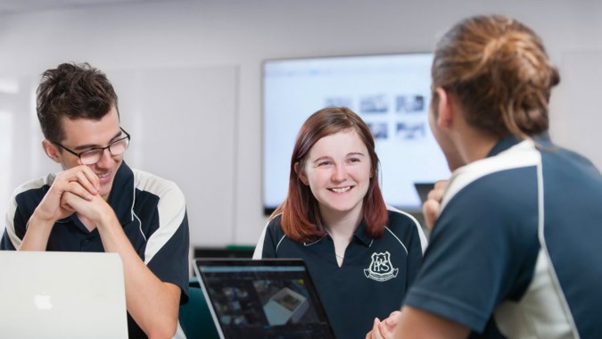 Drei Schüler der Willunga High School führen ein Gespräch in einer akademischen Umgebung mit Computer im Hintergrund.